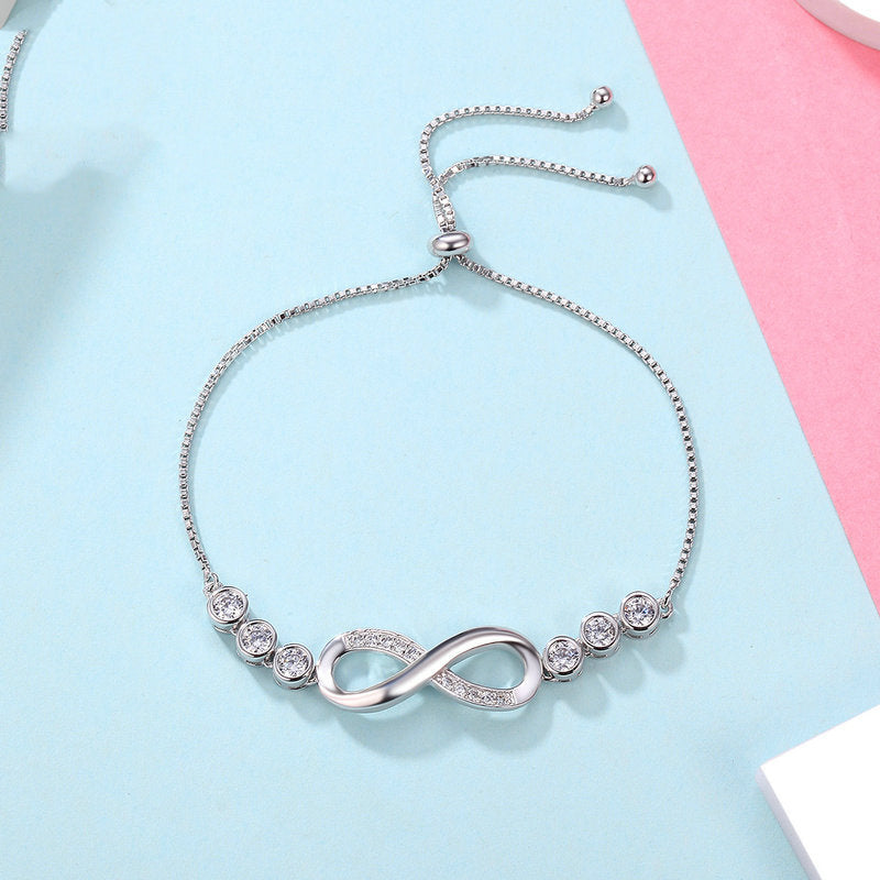 Silver bracelet with infinity symbol on a light blue and pink background