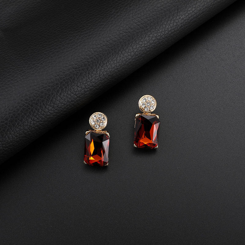 Pair of earrings with red gemstones on a black fabric background