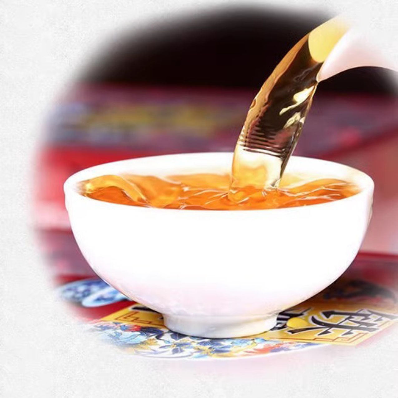 Tea being poured into a white ceramic teacup with a blurred background