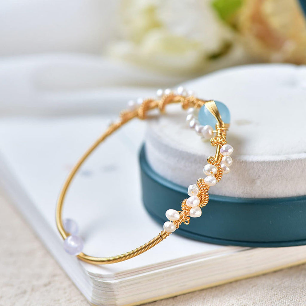 Gold bracelet with pearls on a white surface with a blurred background