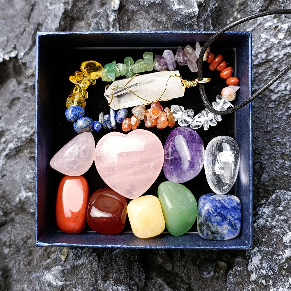 Box of various colorful crystals and necklaces on a stone background