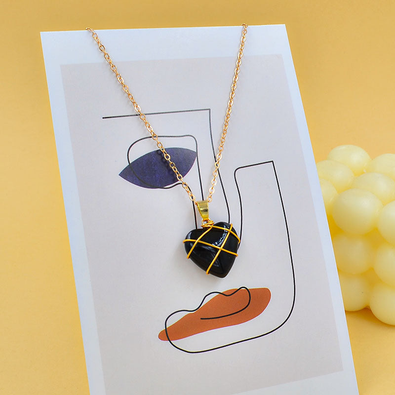Necklace with a heart-shaped pendant on a card with abstract designs, against a yellow background.