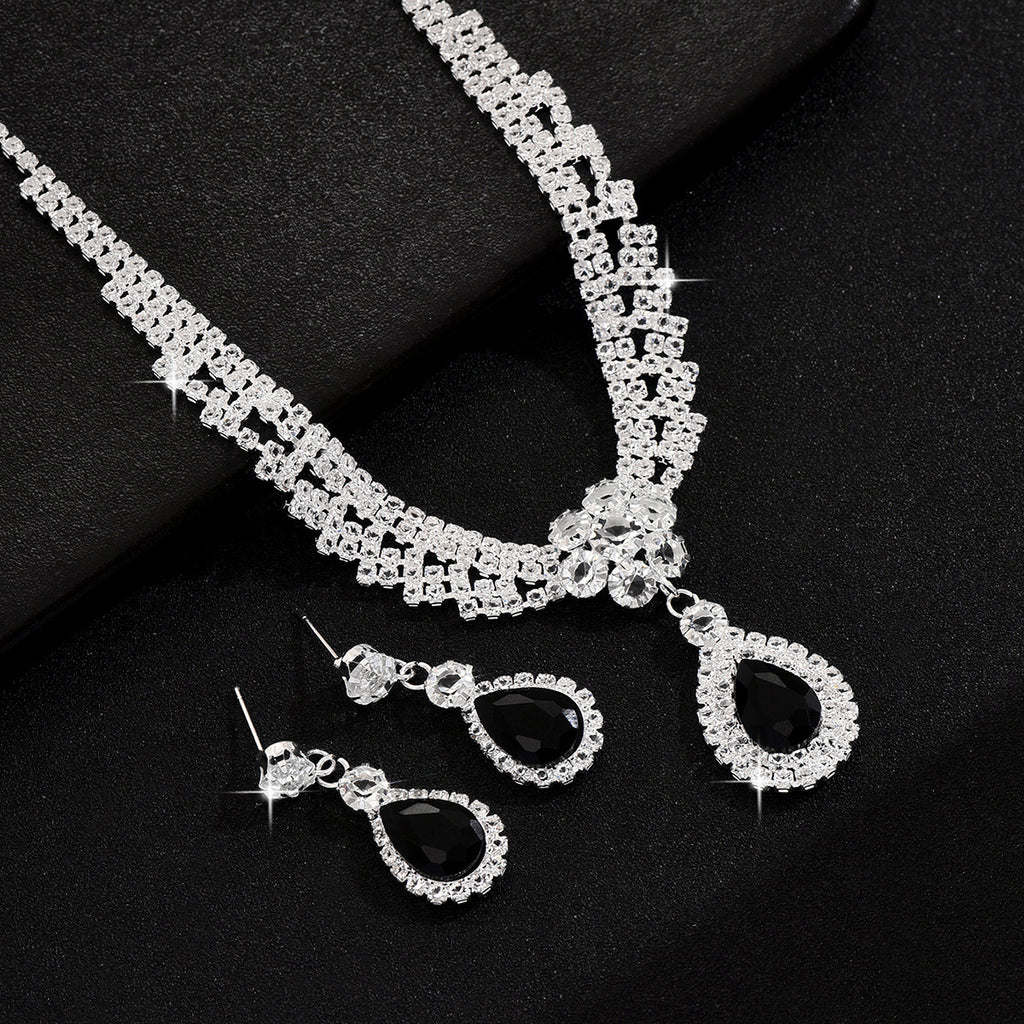 Silver necklace and earrings set on a black background