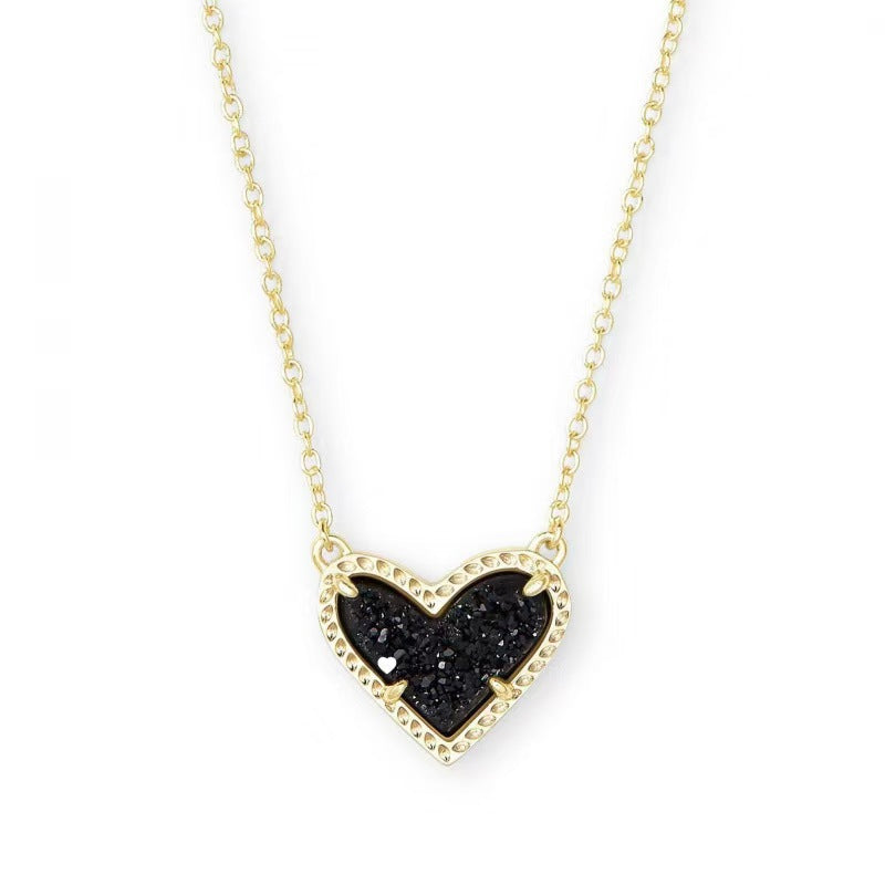 Necklace with a black heart-shaped pendant on a gold chain against a white background