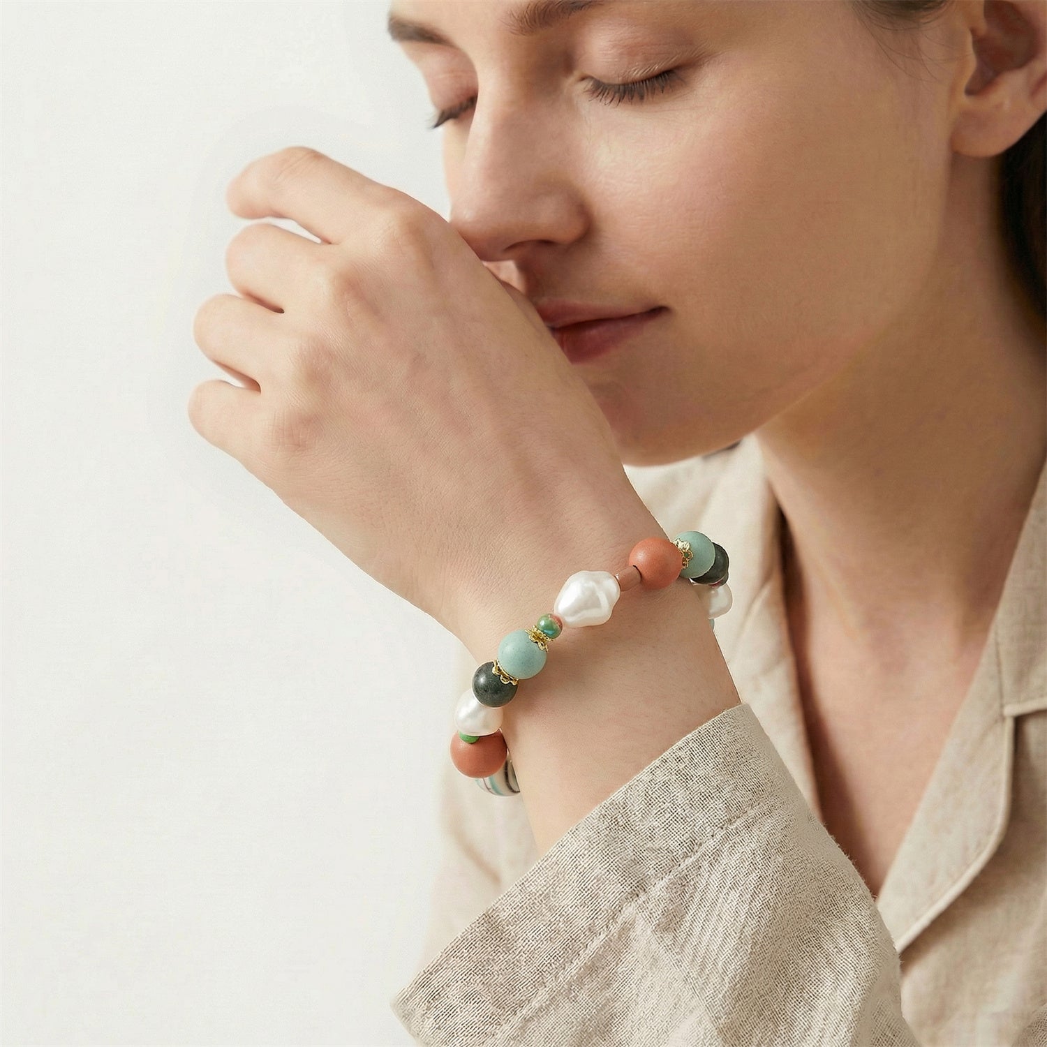 Woman wearing a colorful beaded bracelet on a plain background