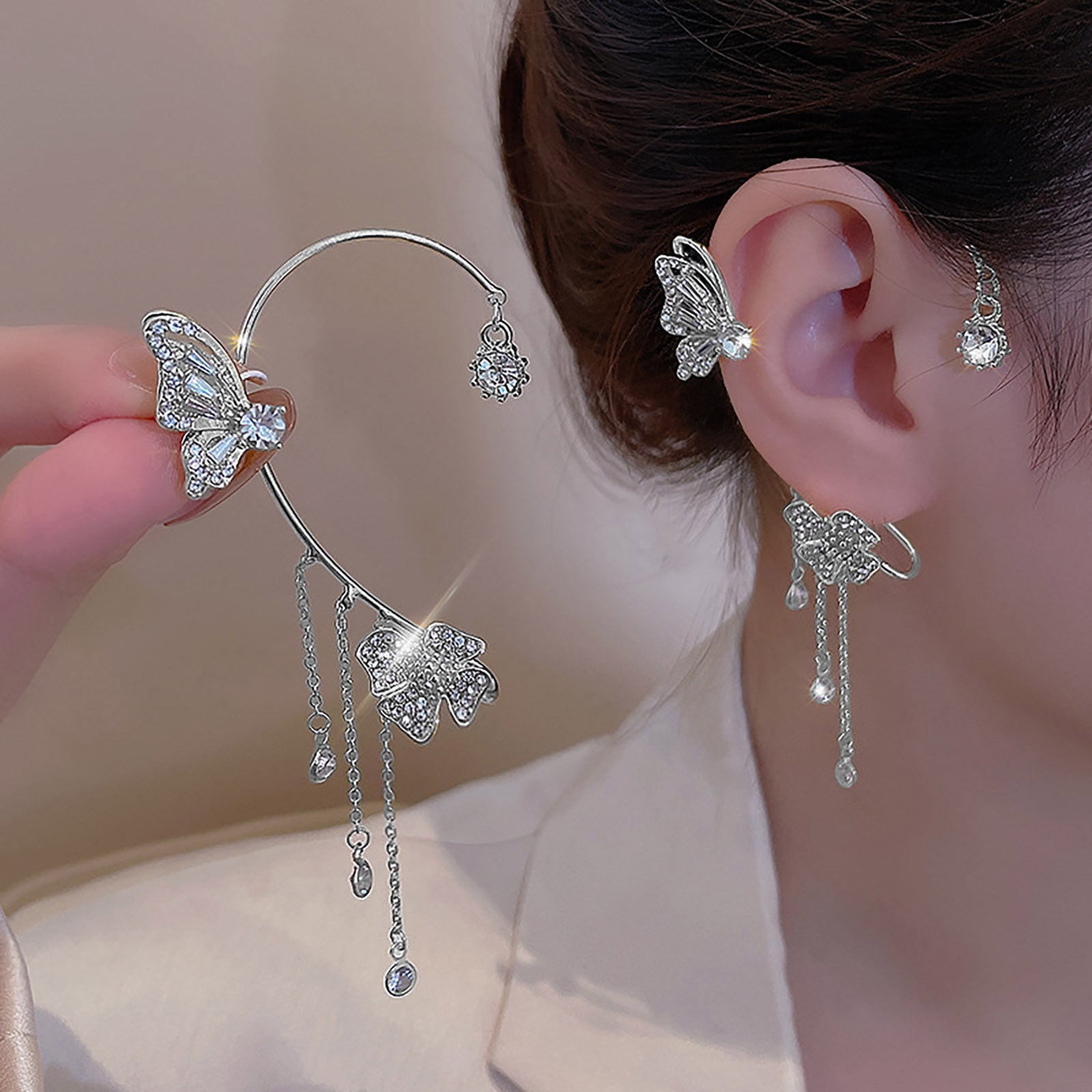 Butterfly-shaped earrings with dangling elements worn by a person.