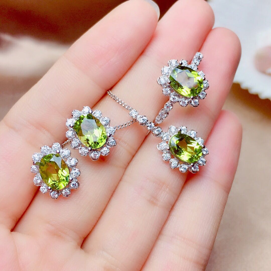 Peridot earrings on a hand with a blurred background