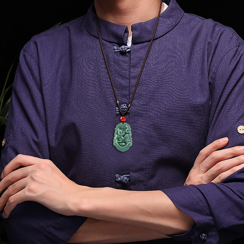 Person wearing a dark blue shirt with a green jade pendant necklace.