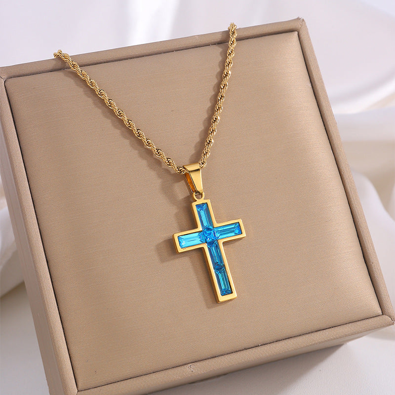 Gold necklace with a blue cross pendant on a beige display box.
