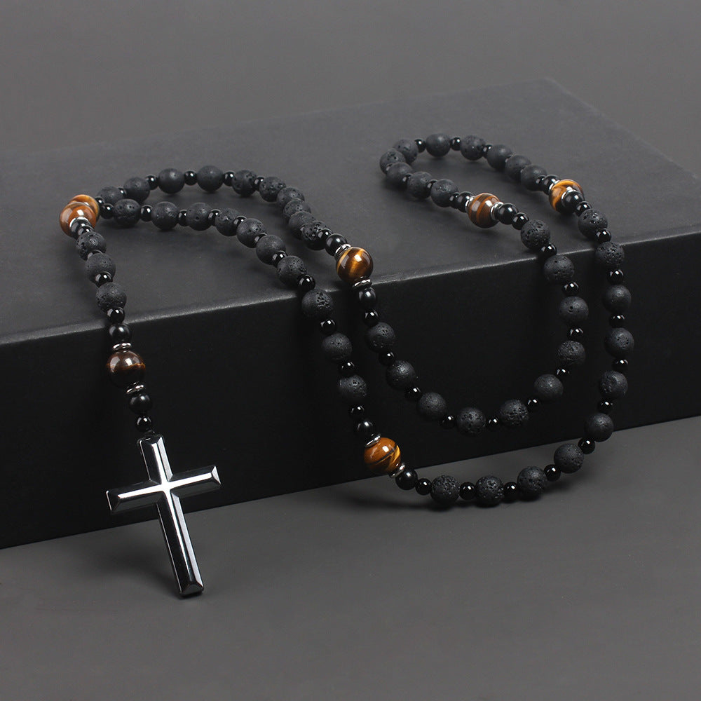 Black beaded necklace with a silver cross pendant on a dark surface