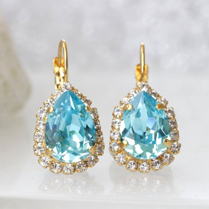 Teardrop-shaped blue gemstone earrings with gold accents on a light background