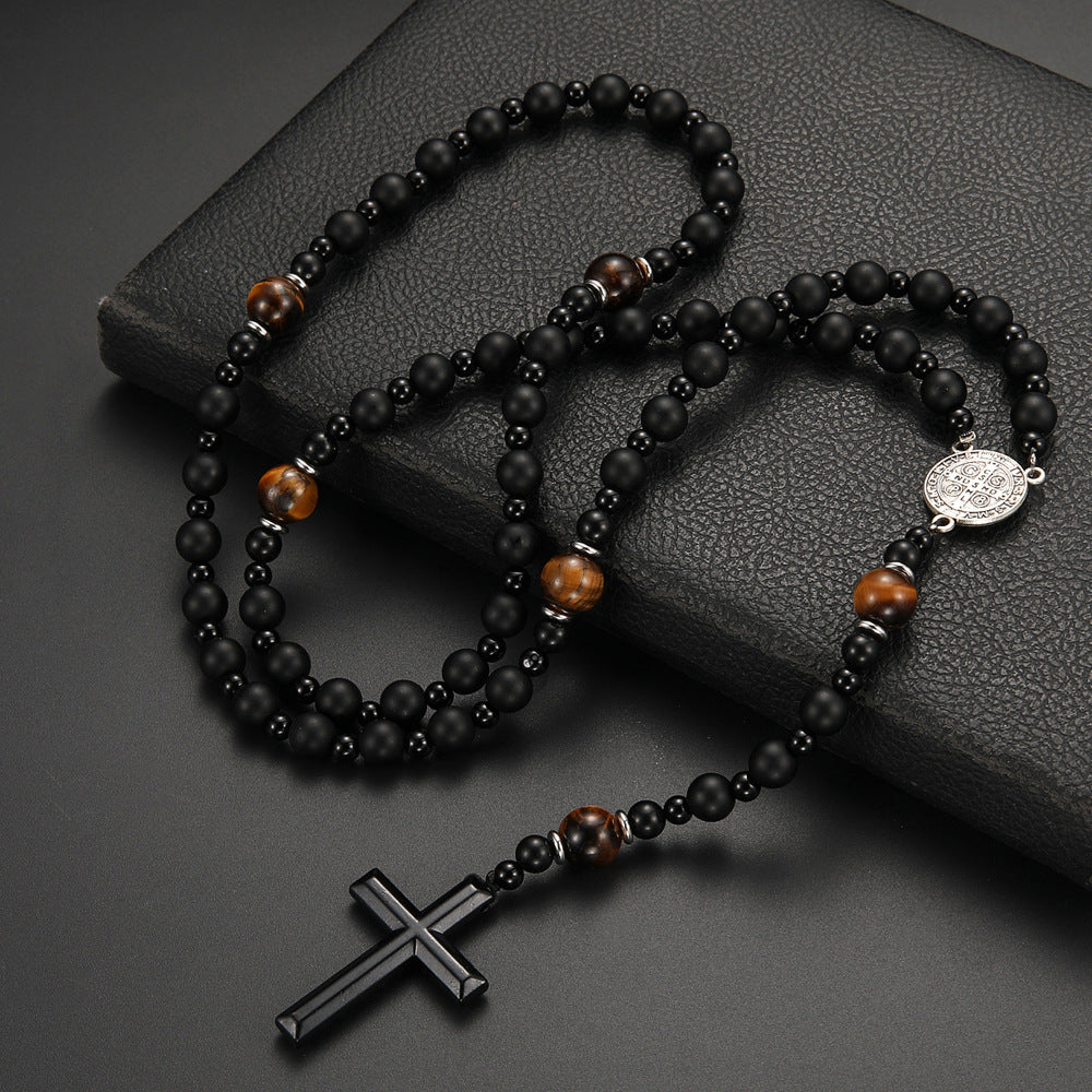 Black and brown beaded rosary with a cross on a dark textured surface
