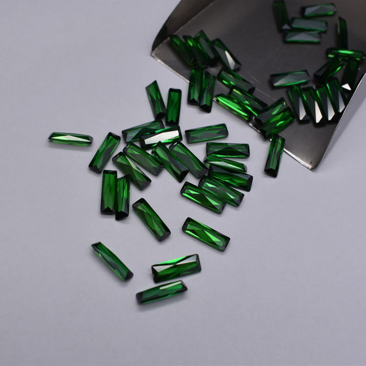 Green gemstones scattered on a gray surface with a metal scoop.