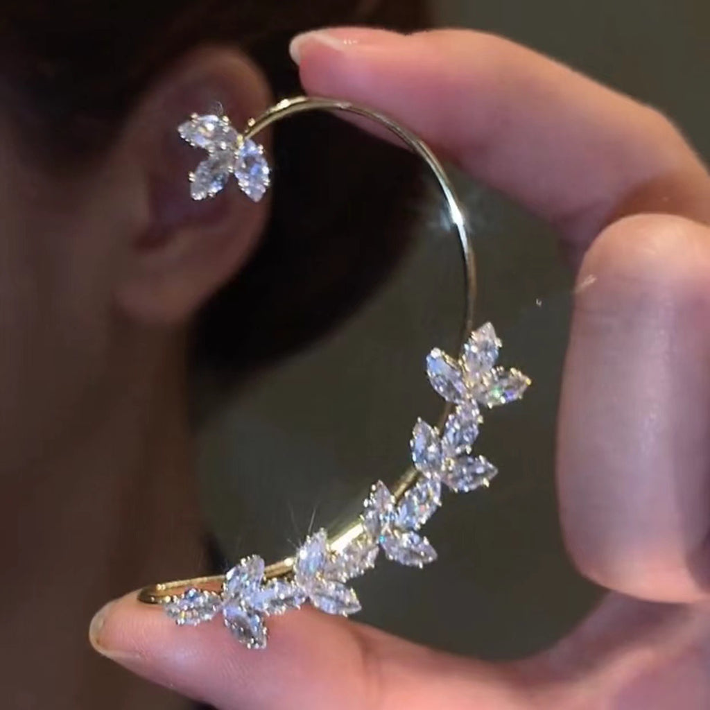 Close-up of a hand holding a diamond earring with a blurred background