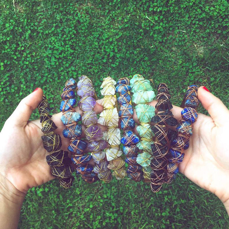 Colorful beaded bracelets held in hands against a grassy background