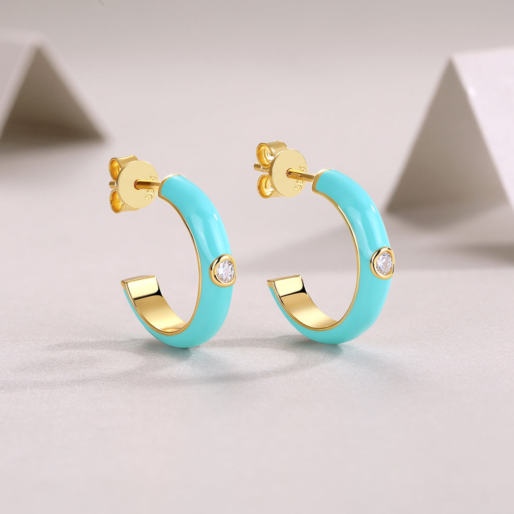 Turquoise hoop earrings with gold accents on a light gray background