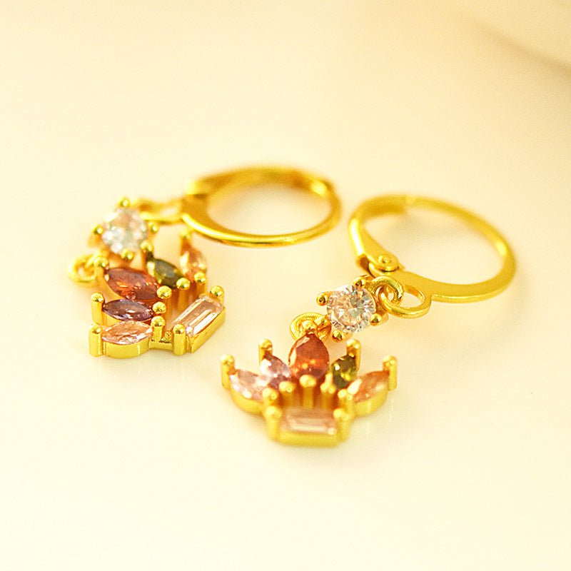 Gold earrings with gemstones on a yellow background