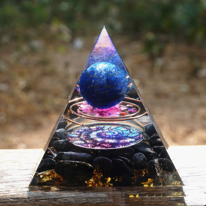 Pyramid-shaped crystal with a blue sphere inside, set against a natural background.