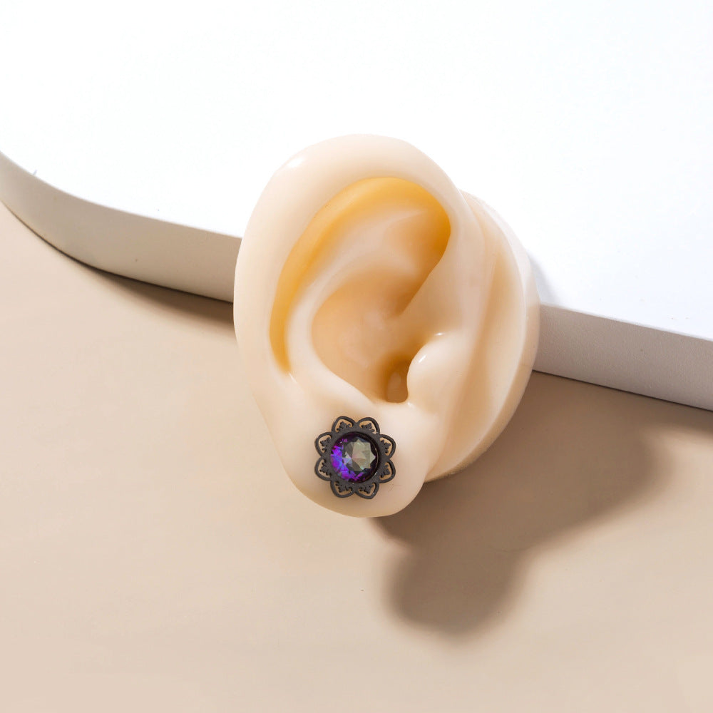 Close-up of a decorative earring shaped like an ear with a gemstone on a white background
