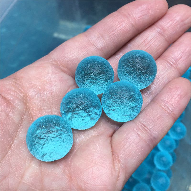 Hand holding blue gel beads with a pool background