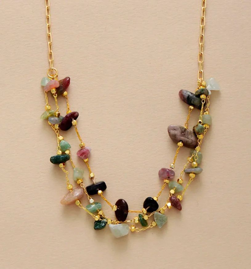 Necklace with multicolored stones and gold chain on beige background