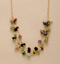 Necklace with multicolored stones and gold chain on beige background