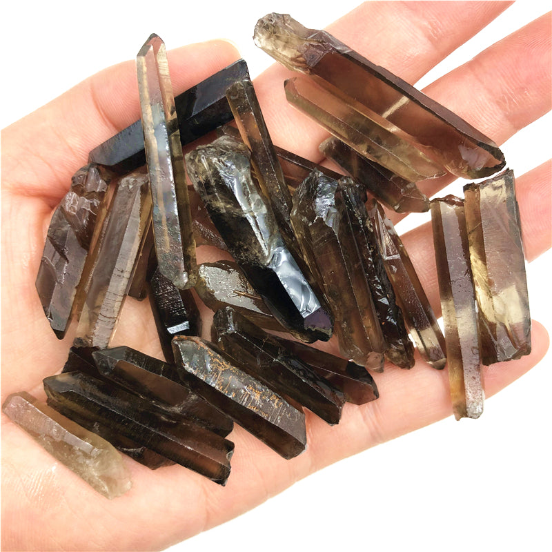 Hand holding a collection of brown crystal pieces on a white background