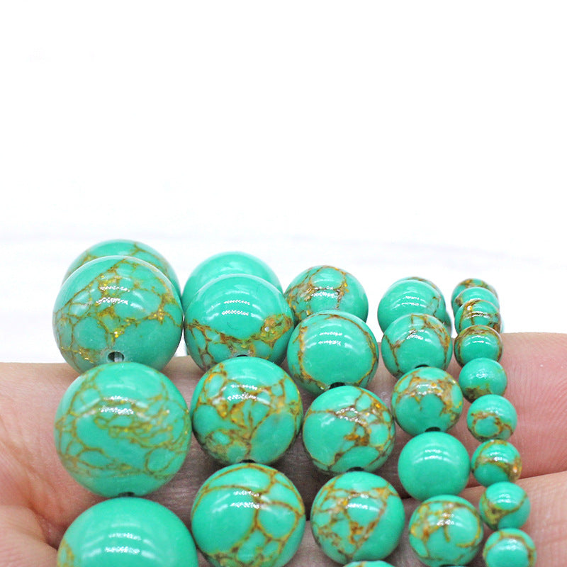 Turquoise beads with gold marbling held in a hand against a white background
