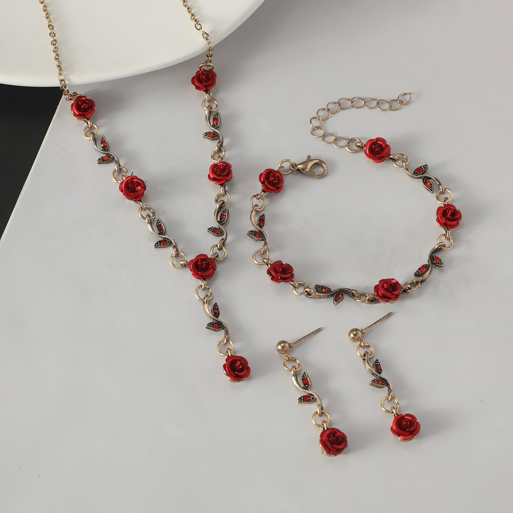 Jewelry set with red rose details on a white surface
