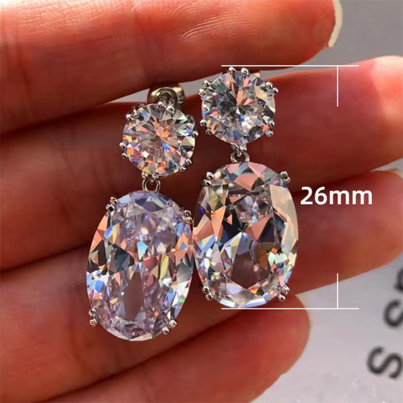 Crystal earrings held between fingers with a measurement label indicating 26mm.