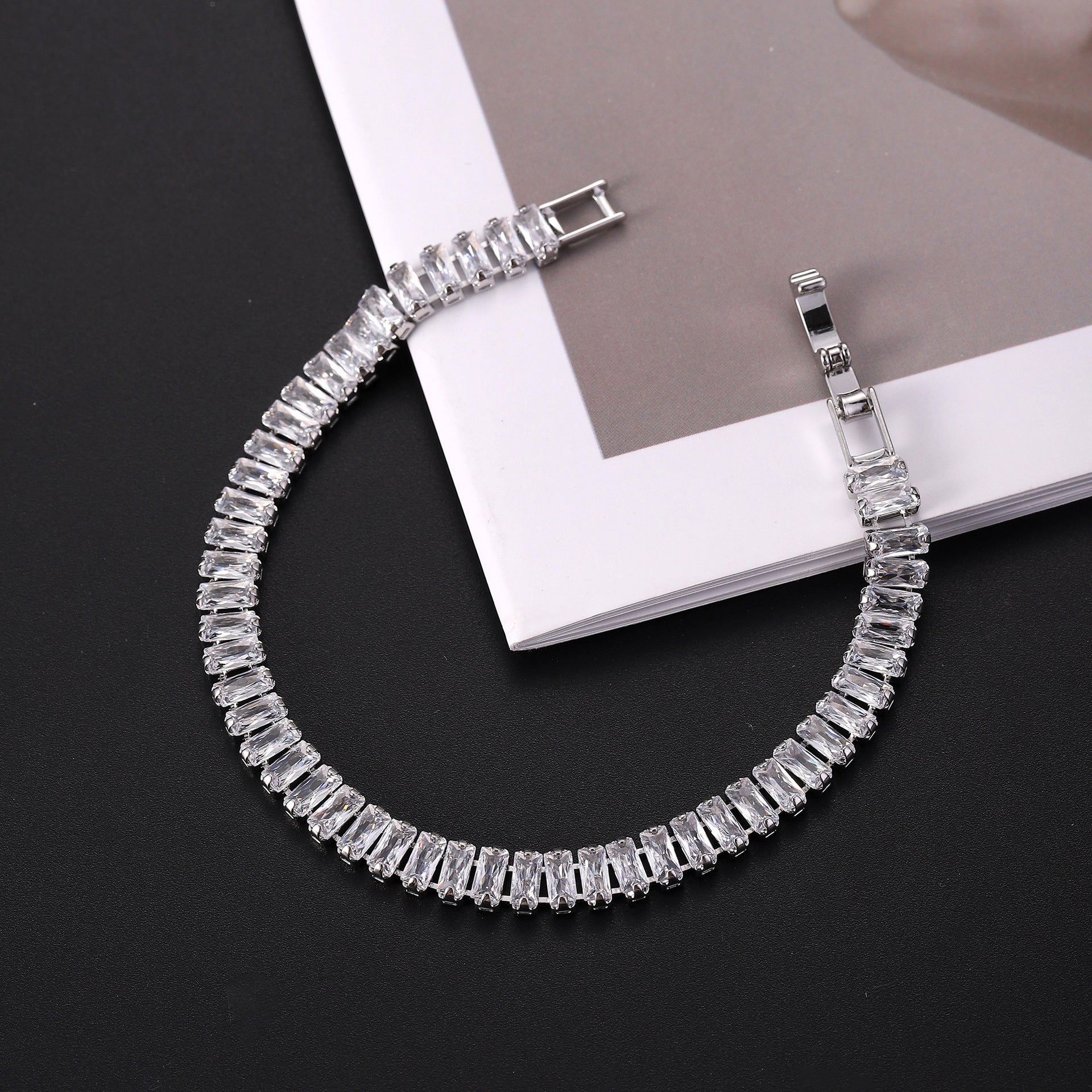 Silver bracelet with clear stones on a black surface