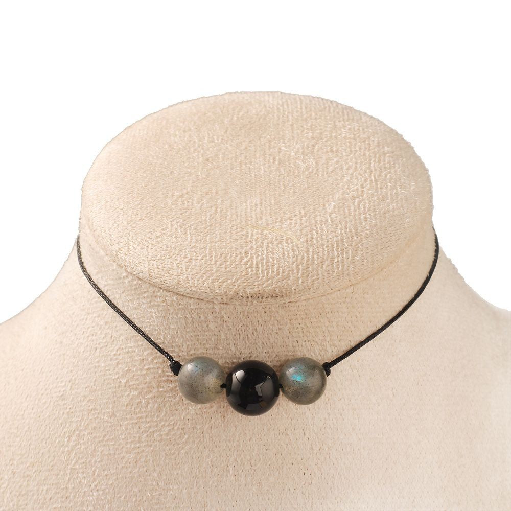 Necklace with three beads on a mannequin bust against a white background