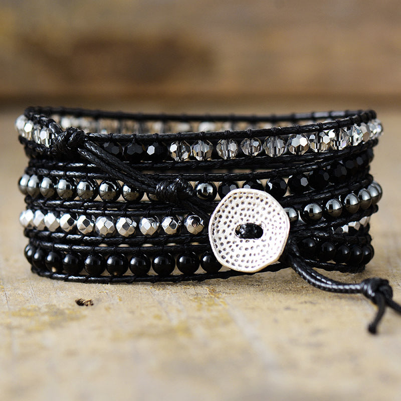 Multi-layered bracelet with beads and a button clasp on a wooden surface