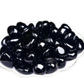 Black jelly beans on a white plate with a white background
