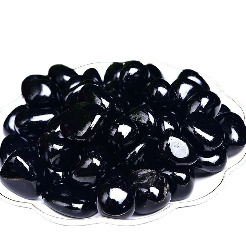 Black jelly beans on a white plate with a white background
