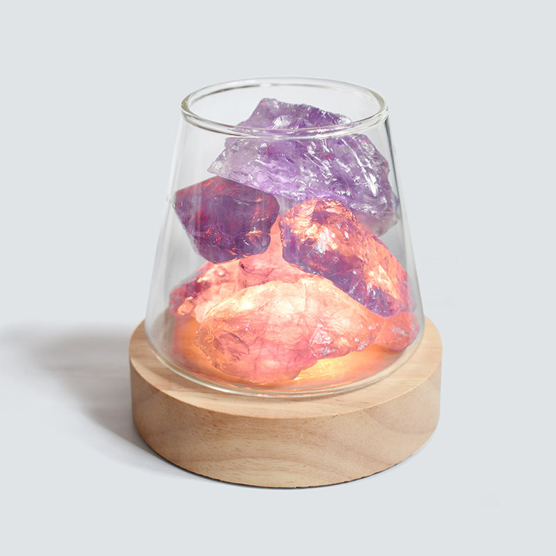 Decorative lamp with natural rocks inside a glass container on a wooden base.