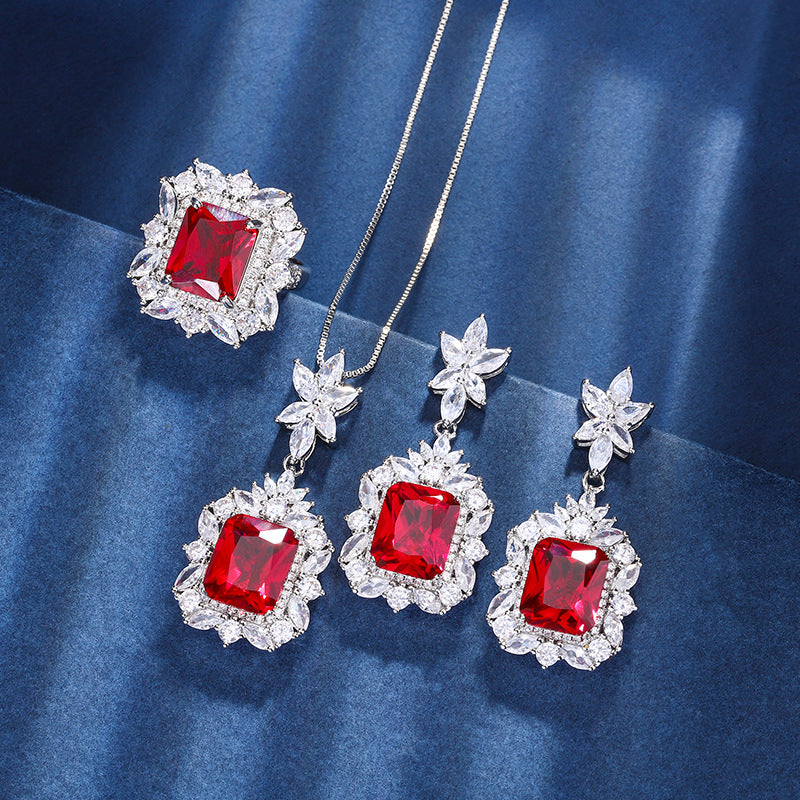 Jewelry set with red gemstones and silver flowers on a blue fabric background