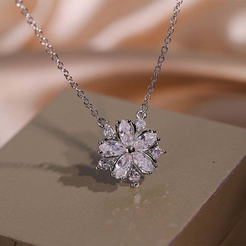 Silver necklace with a floral pendant on a beige surface