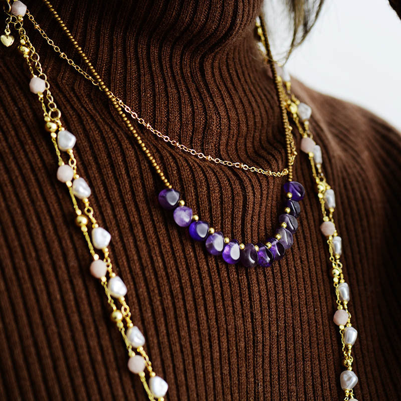 Necklace with purple and white beads on a brown ribbed sweater