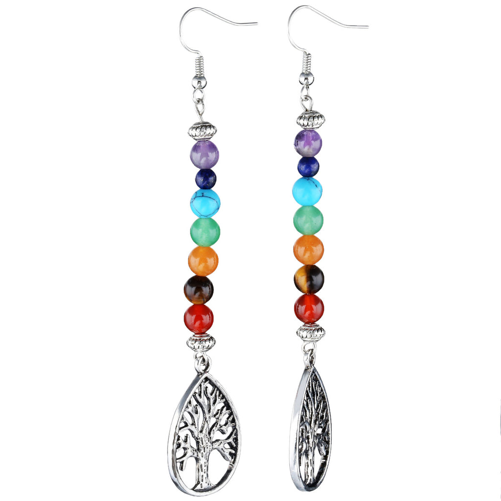 Pair of beaded earrings with tree of life charms on a white background
