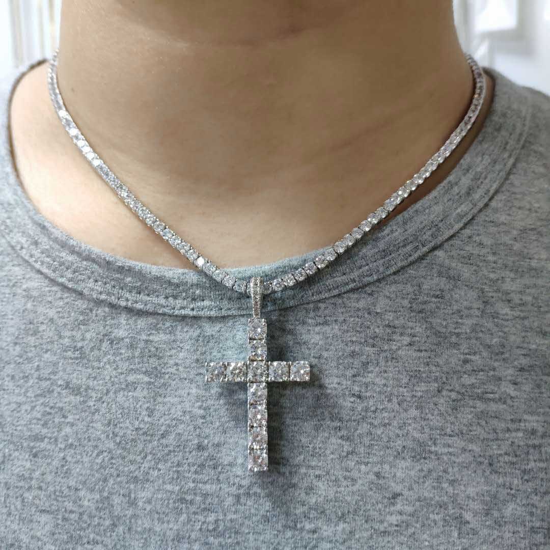 Necklace with a cross pendant worn by a person in a gray shirt