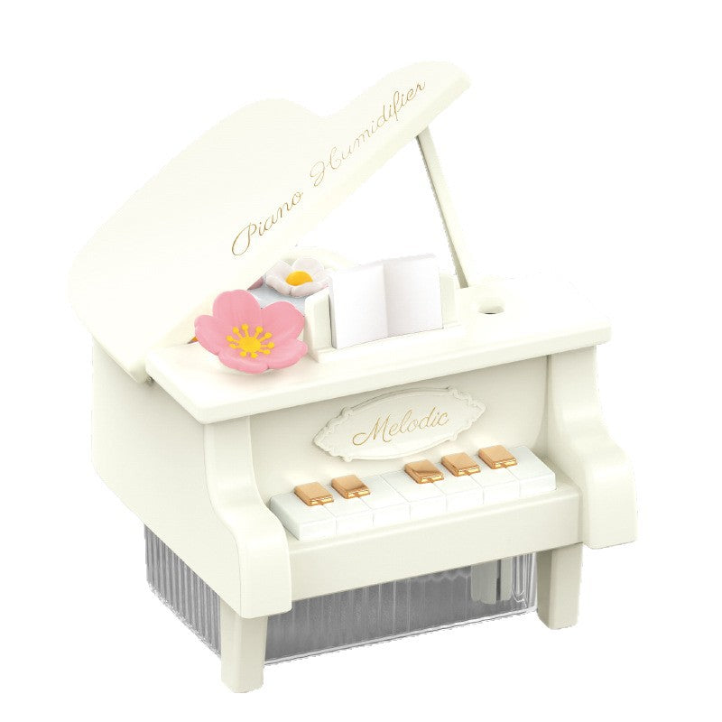 Small white toy piano with pink flower and decorative elements on a white background