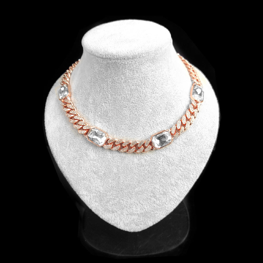 Necklace with rose gold chain and clear crystals on a white stand against a black background