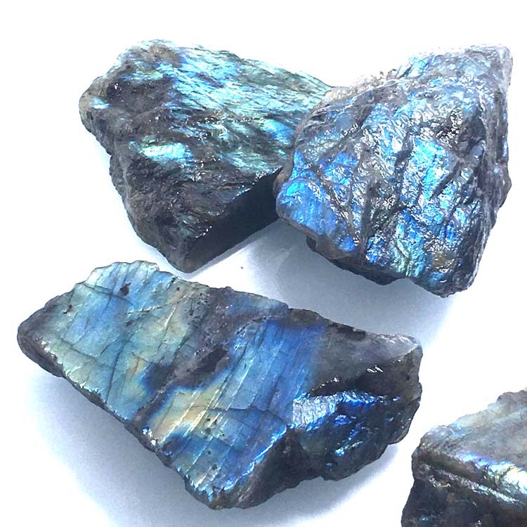 Three rough labradorite stones on a white background