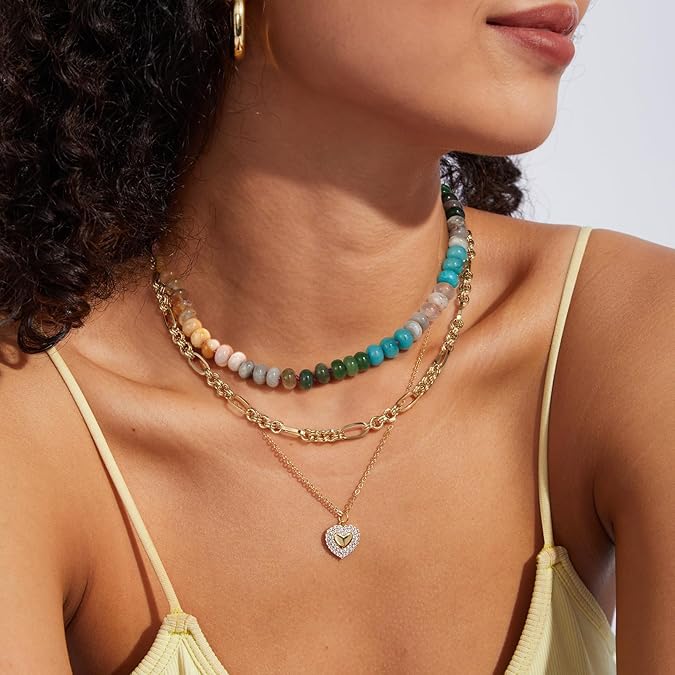 Close-up of a woman wearing multiple necklaces with a neutral background