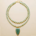 Two beaded necklaces with a green pendant on a beige background