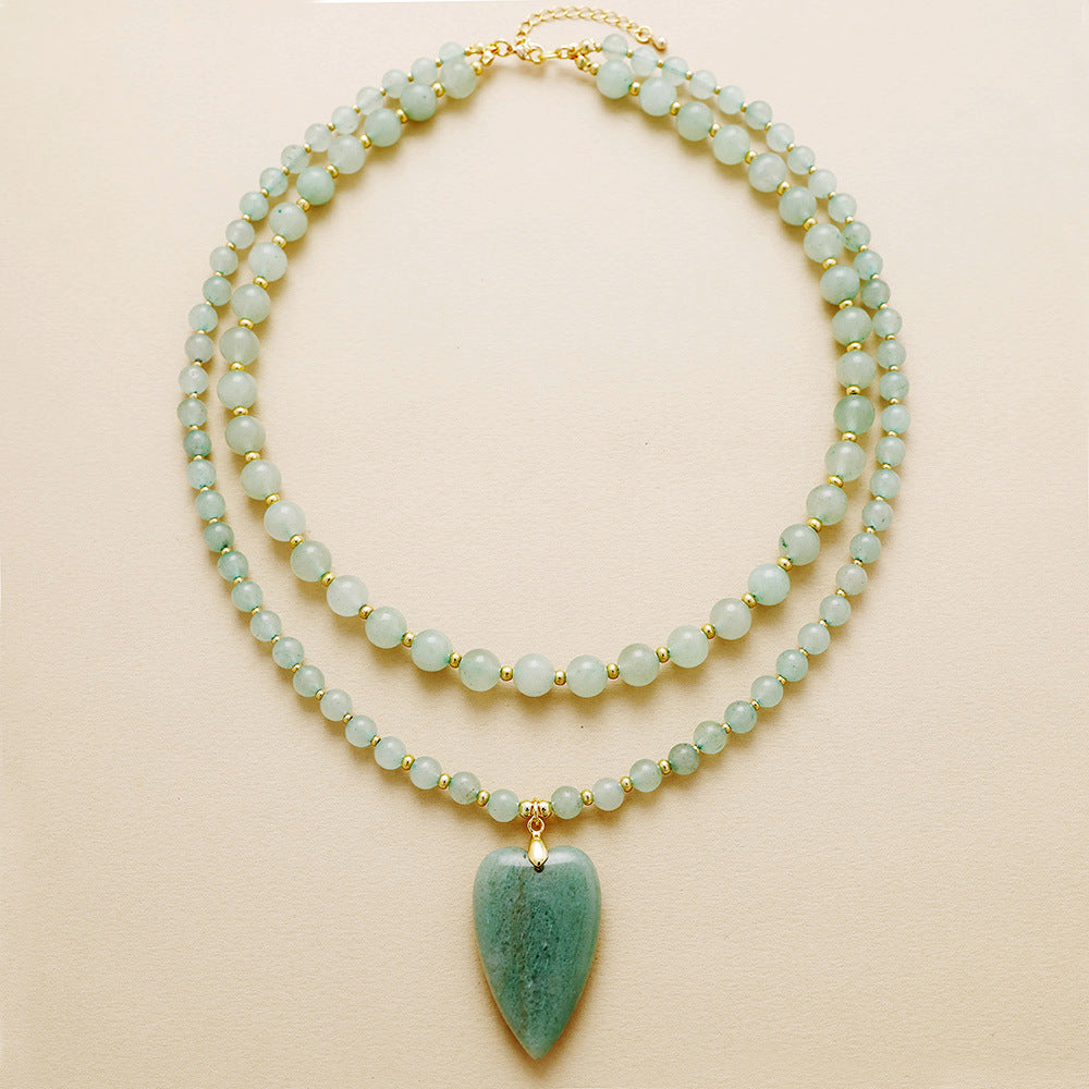 Two beaded necklaces with a green pendant on a beige background