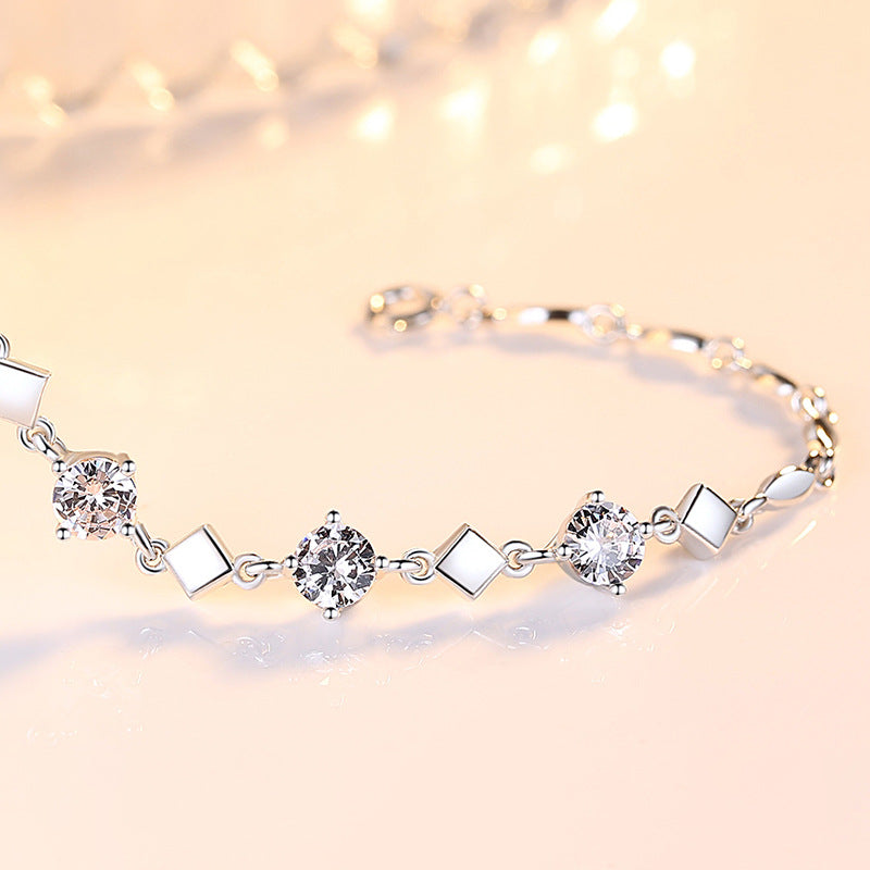 Silver bracelet with diamond-like stones on a soft pink background
