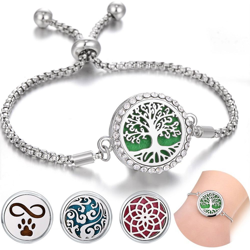 Silver bracelet with tree of life charm and three additional charms on a white background