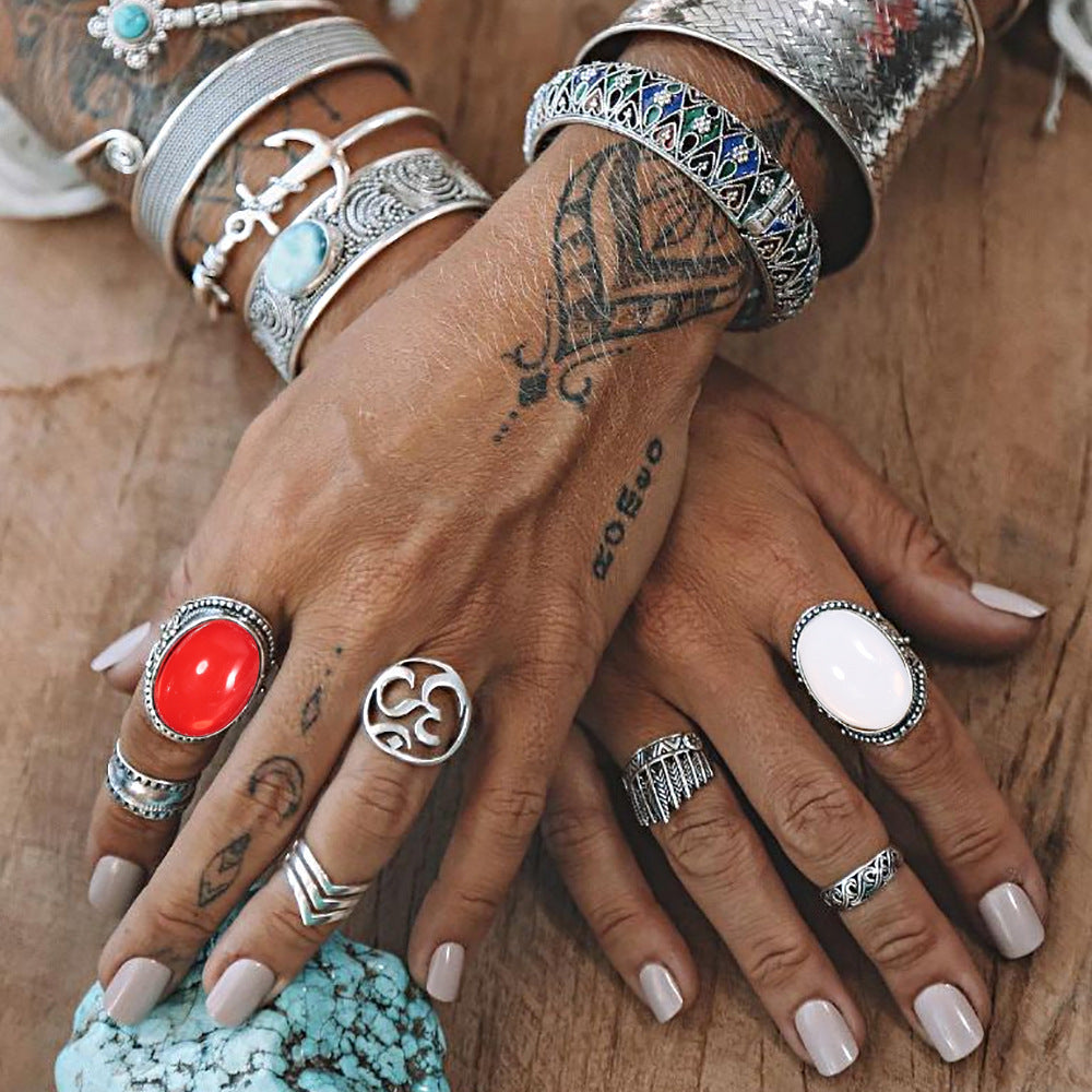 Close-up of a hand with multiple silver rings and bracelets on a wooden surface